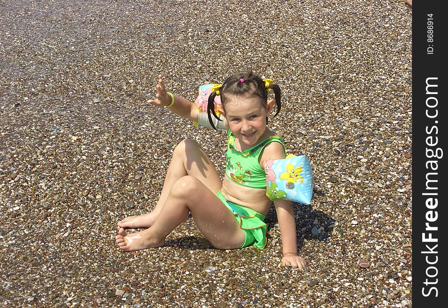 A girl in a green swimming suit plays the bank near water. A girl in a green swimming suit plays the bank near water.