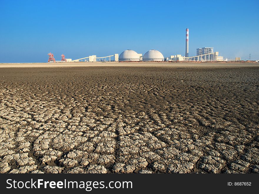 Cracks of dried Seabed backgrounded by a power Plant. Cracks of dried Seabed backgrounded by a power Plant