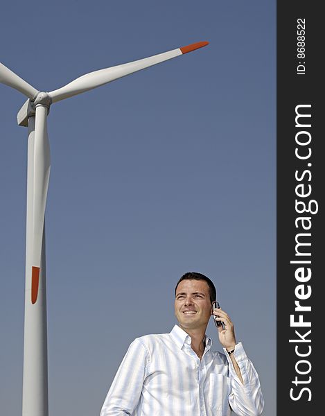 Man and wind turbines; young adult uses cellular with wind turbines in background