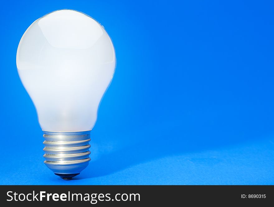 Illuminated light bulb on blue studio lit background