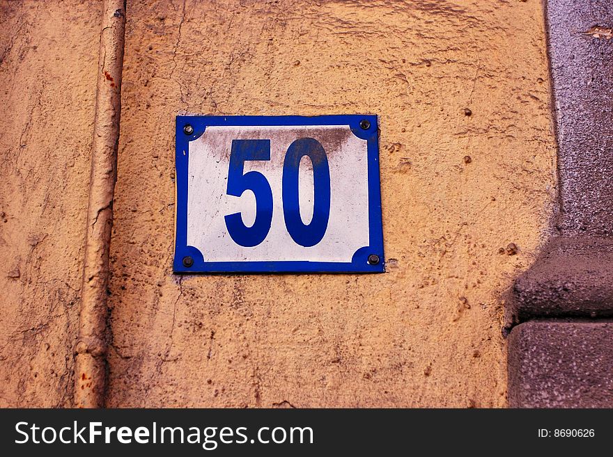 Old dusty street number plaque on grungy wall.