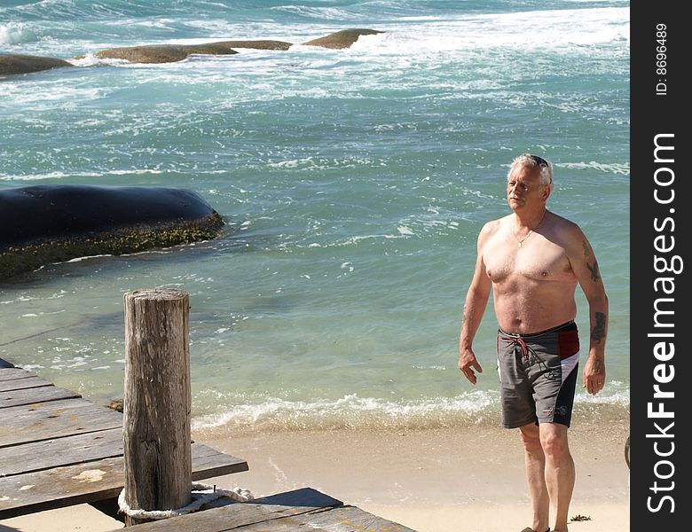 This senior man is enjoying a stroll on the beach with the ocean tide rolling in. This senior man is enjoying a stroll on the beach with the ocean tide rolling in.