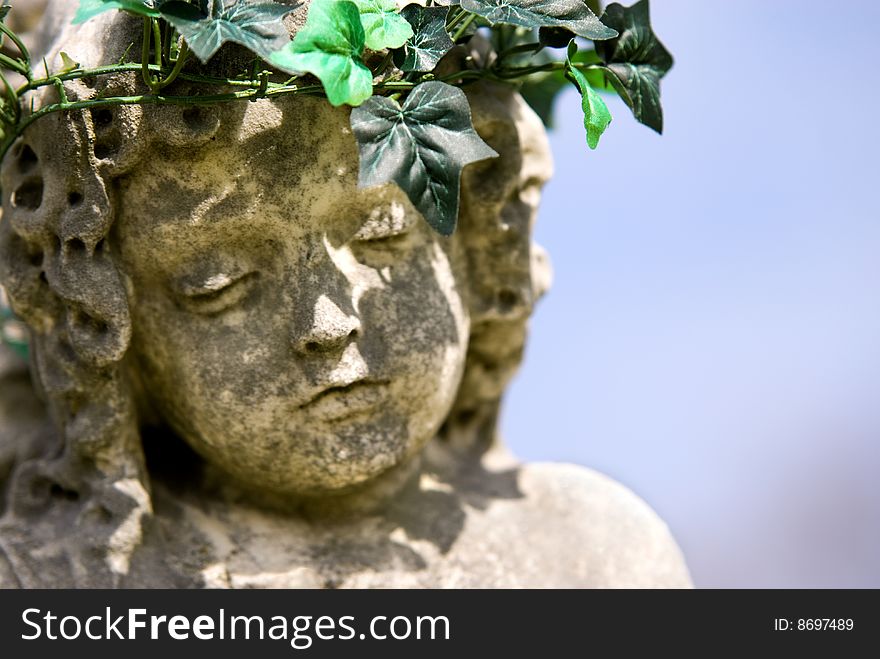 A closeup of a stone statue of a child angel face with ivy at Mount Olivet Cemetery in Nashville, TN. copy space. A closeup of a stone statue of a child angel face with ivy at Mount Olivet Cemetery in Nashville, TN. copy space