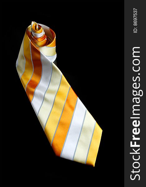 An orange necktie with stripes on black background. An orange necktie with stripes on black background.