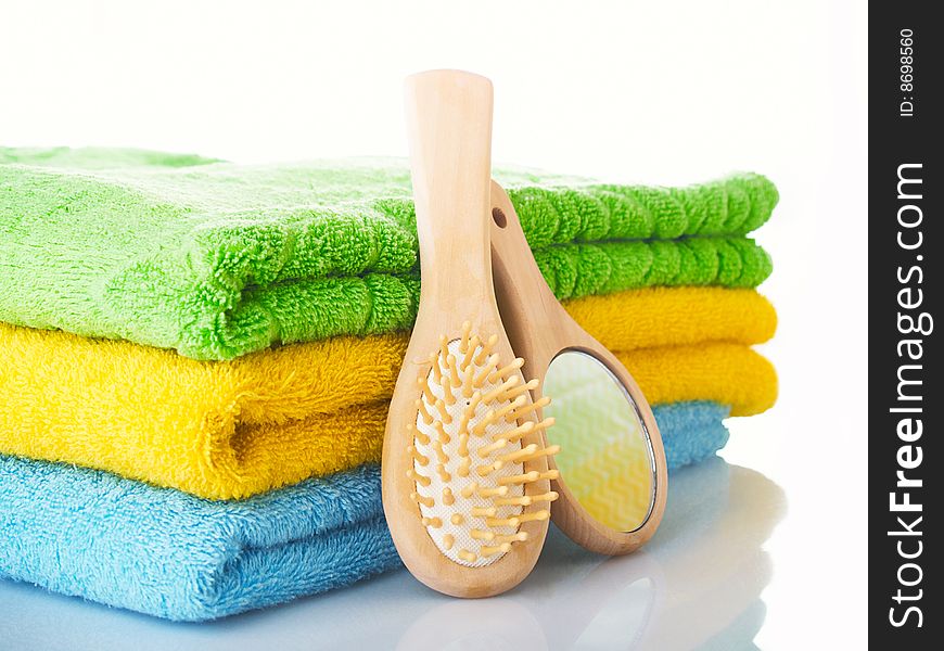 Three terry multi-coloured towels on a table, hairbrush a mirror