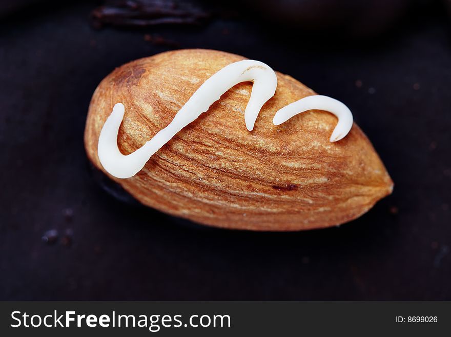 Small decorated almond on the dark chocolate. Narrow depth of field. Macro. Small decorated almond on the dark chocolate. Narrow depth of field. Macro.