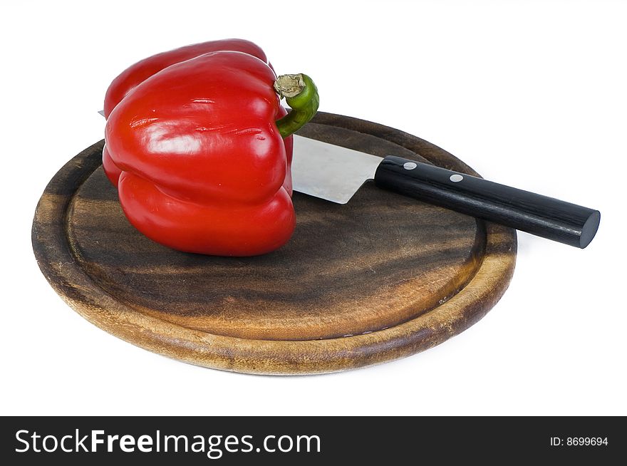 Fresh sweet pepper and table knife on brown hardboard. Fresh sweet pepper and table knife on brown hardboard