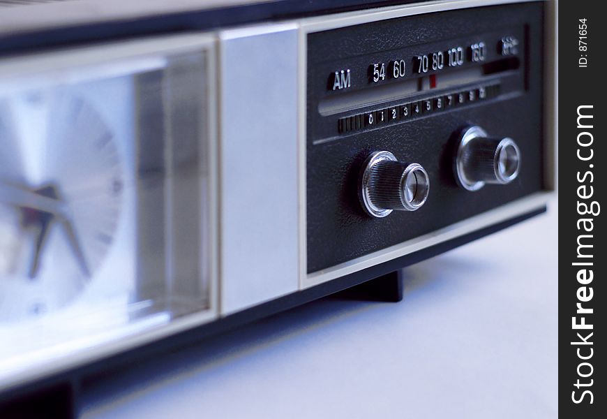 Vintage AM-band analog clock radio with radio dial in very shallow focus, in muted light. Vintage AM-band analog clock radio with radio dial in very shallow focus, in muted light.