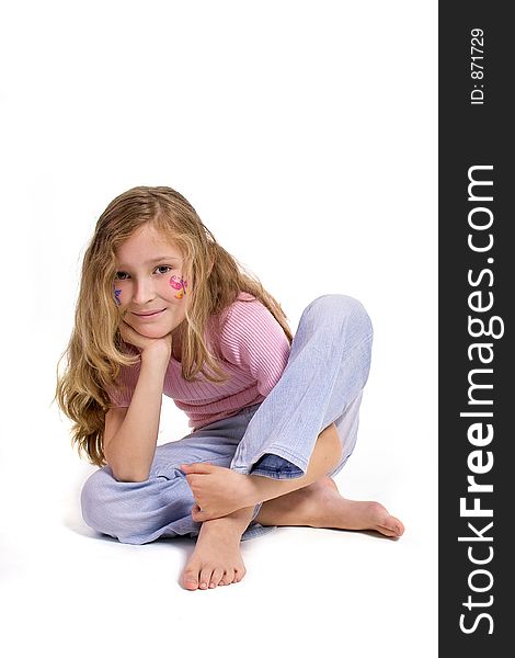 Beautiful young girl with a flower and butterfl drawing on her cheek sitting on the floor looking direct. Beautiful young girl with a flower and butterfl drawing on her cheek sitting on the floor looking direct