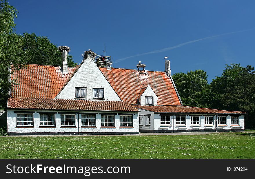 A white house. On the roof are some nest with storks.