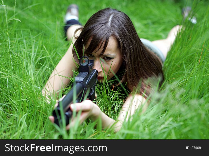 A Girl lying in grass with a shotgun. A Girl lying in grass with a shotgun
