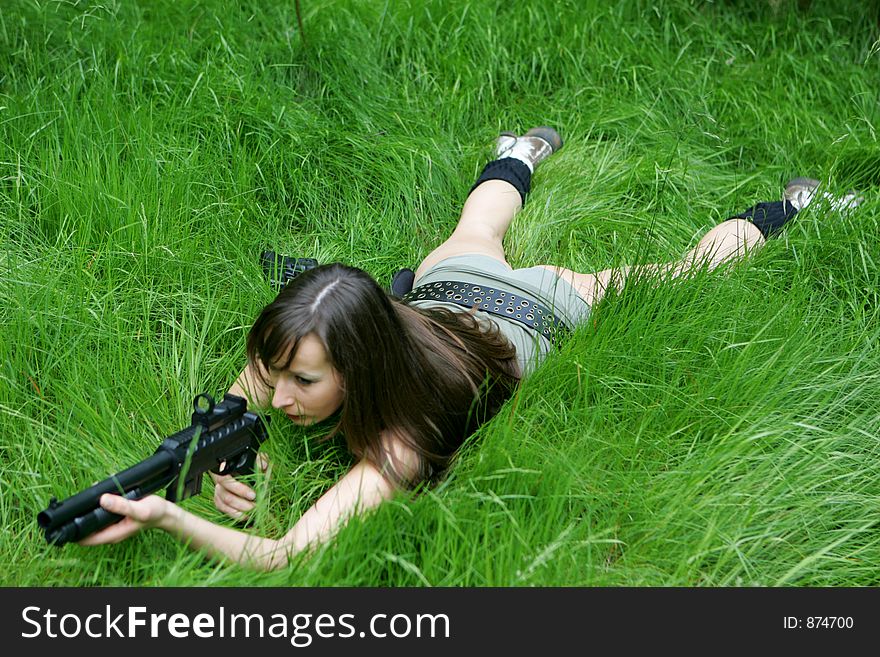 A girl lying in grass with a shotgun. A girl lying in grass with a shotgun