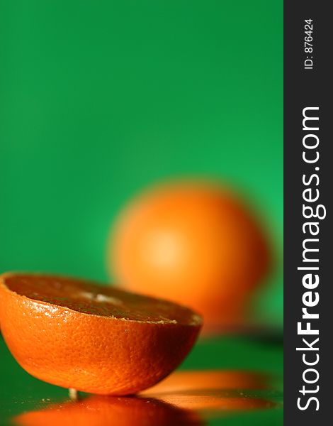 Close up picture ofan orange shot on a green reflecting background