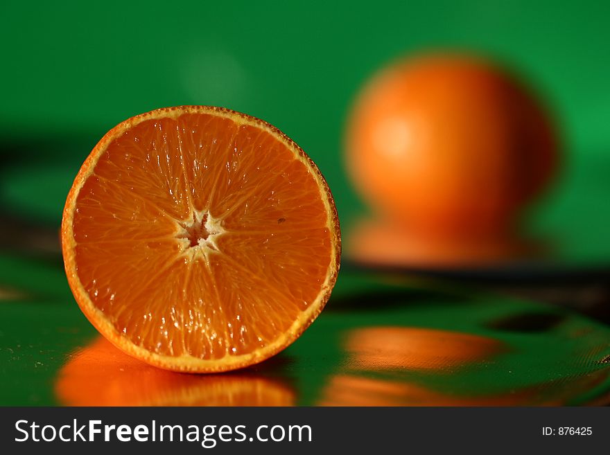 Close up picture ofan orange shot on a green reflecting background
