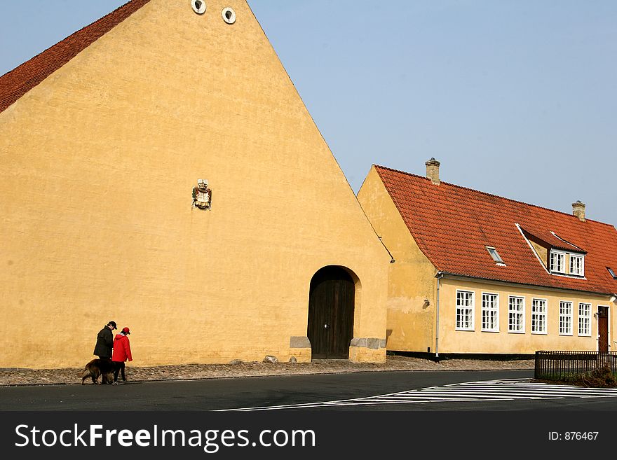 Large yellow l house in denmark a sunny summer day with people passing by. Large yellow l house in denmark a sunny summer day with people passing by