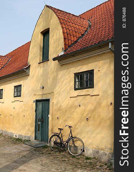 Large yellow l house a sunny summer day with a bike in a village in denmark. Large yellow l house a sunny summer day with a bike in a village in denmark