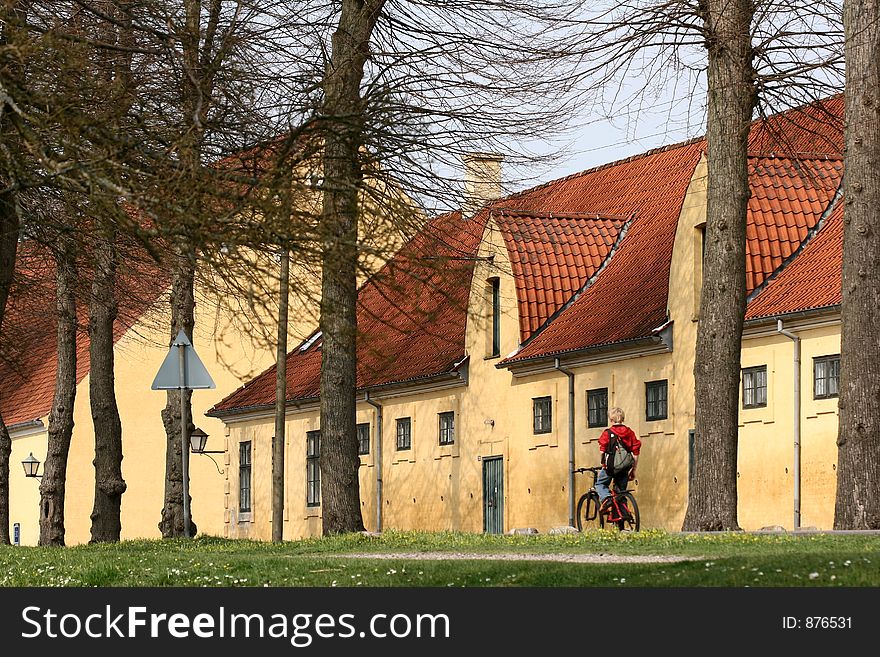 Large yellow l house   a sunny summer day with a boy on bike  in a village in denmark. Large yellow l house   a sunny summer day with a boy on bike  in a village in denmark