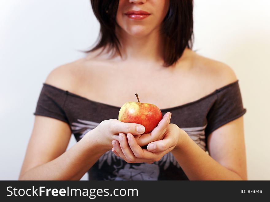 A beautiful young woman holding an apple in her hand. sharpness on the apple. A beautiful young woman holding an apple in her hand. sharpness on the apple.