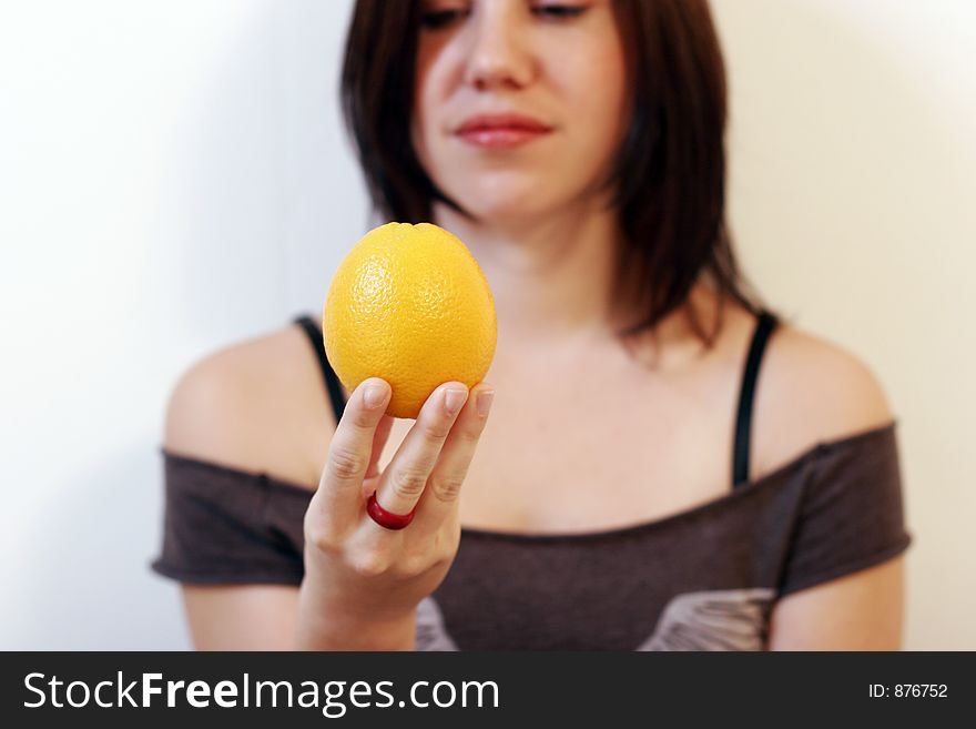 A beautiful young woman holding an orange in her hand. sharpness on the orange. A beautiful young woman holding an orange in her hand. sharpness on the orange.