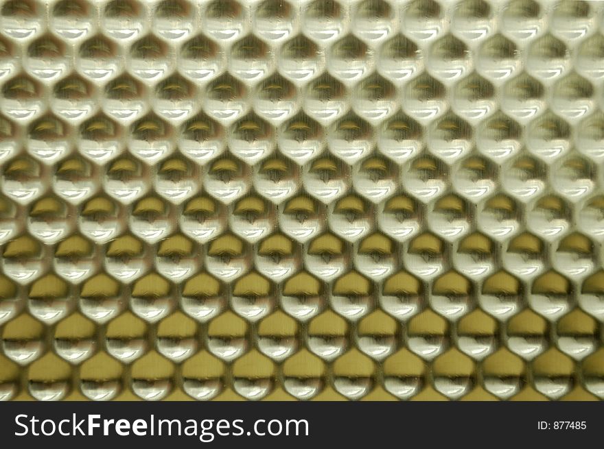 A reflective stamped metal texture with a honeycomb shape. A reflective stamped metal texture with a honeycomb shape