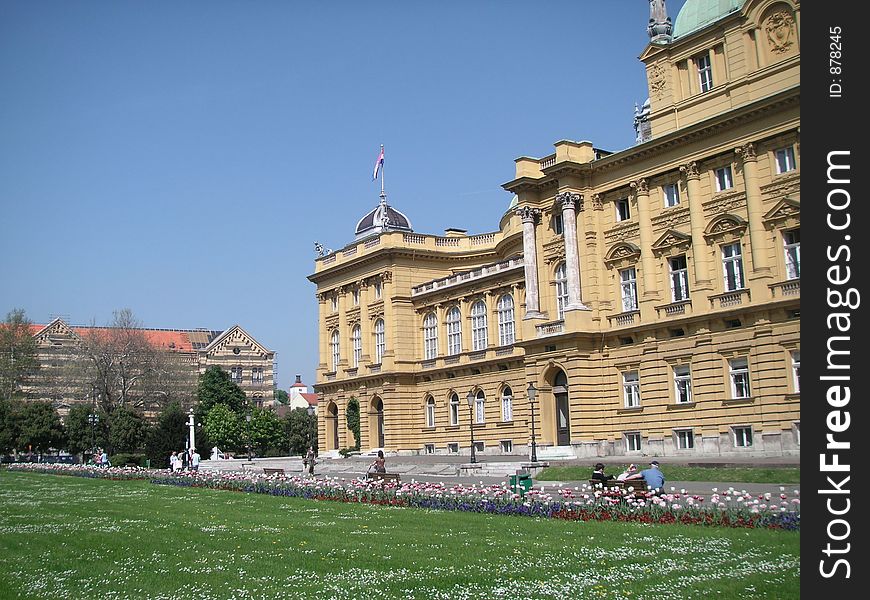 Park with flowers and grass, people resting in front of the neo-baroque building of the Croatian National Theatre (built in 1895). Park with flowers and grass, people resting in front of the neo-baroque building of the Croatian National Theatre (built in 1895).