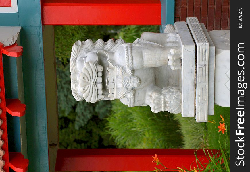 Marble lion figure amidst Chinese-style architectural elements in red and cyan. Marble lion figure amidst Chinese-style architectural elements in red and cyan.