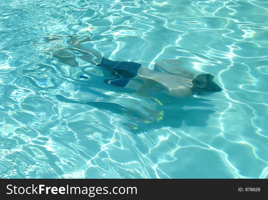 Boy swimming under water in a crystal clear swimming pool. Boy swimming under water in a crystal clear swimming pool.