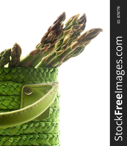 A group of asparagus spears slant to one side of a green woven decortive basket. A group of asparagus spears slant to one side of a green woven decortive basket.