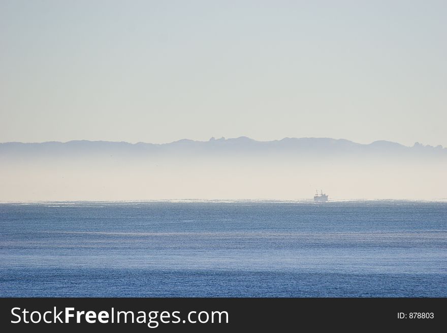 Mist over the ocean with a fishing boat. Mist over the ocean with a fishing boat