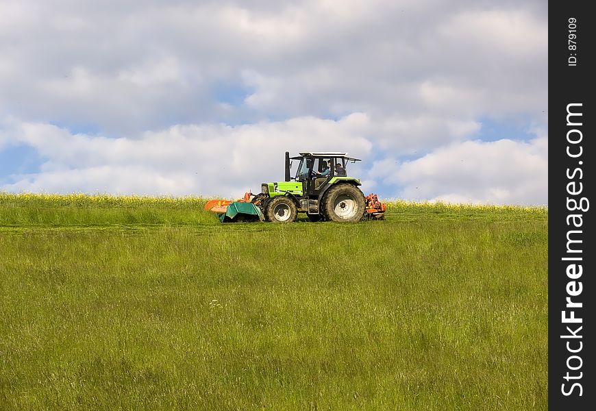 Green tractor mowing a meadow