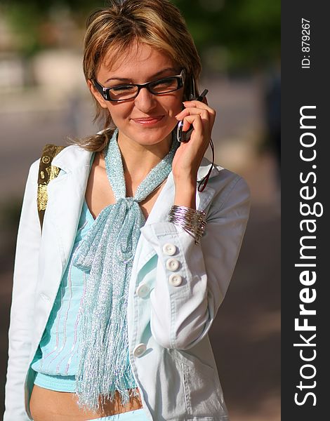 An young woman walking on the street and talking on the phone