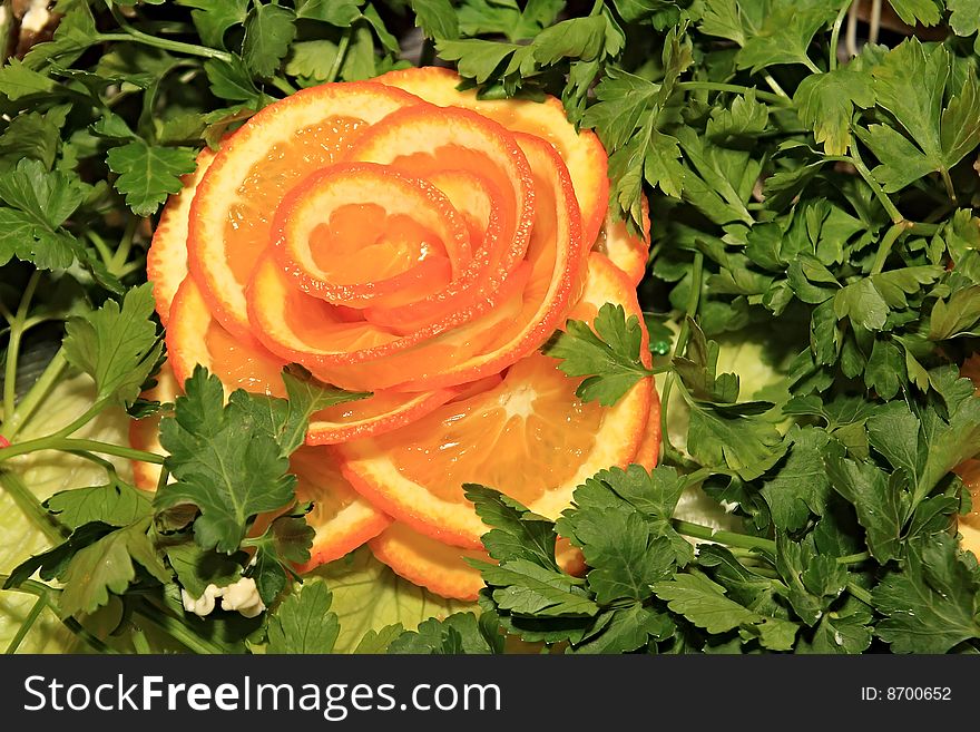 Flower from orange in parsley. Decoration of festive table.