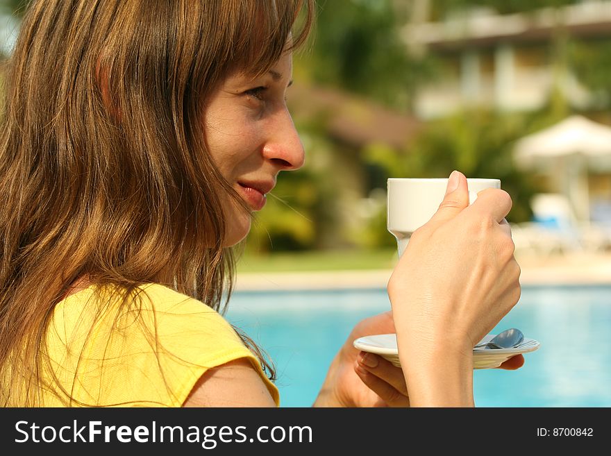 Girl holding a cup coffee by the pool. Girl holding a cup coffee by the pool