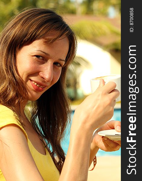 Girl with her coffee cup sitting by the pool. Girl with her coffee cup sitting by the pool