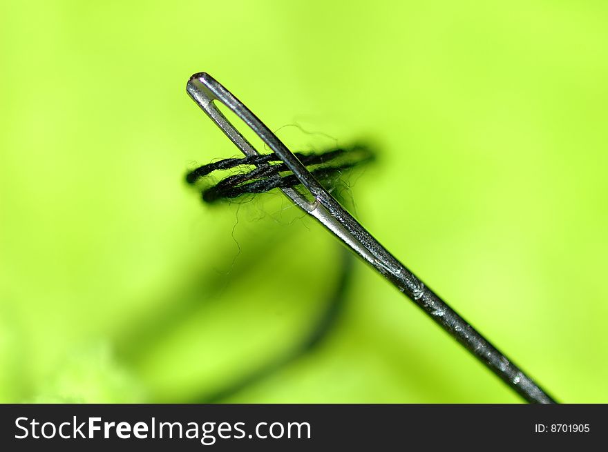 Needle and thread on green background