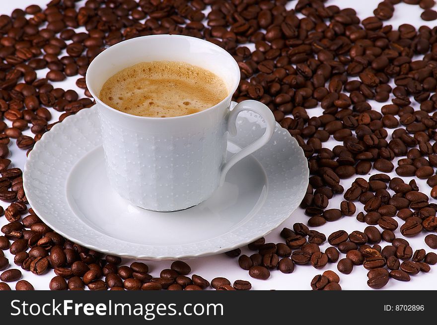 A fresh and tasty cup of coffee with a lot of coffee beans
