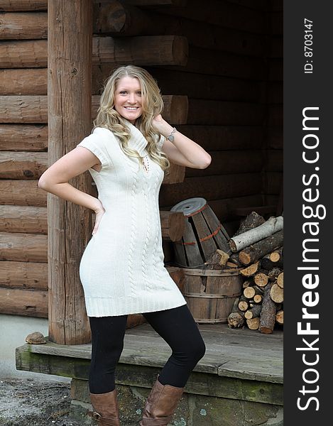 Blond teen girl next to log cabin. Blond teen girl next to log cabin