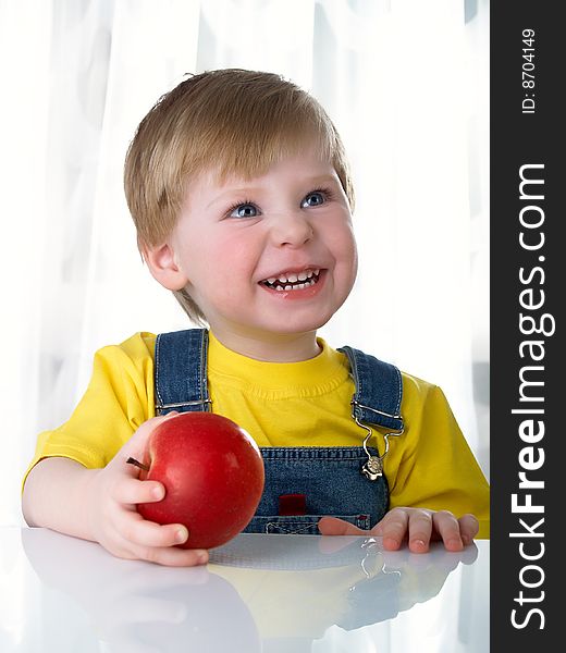 The little boy holds an apple in hands. The little boy holds an apple in hands