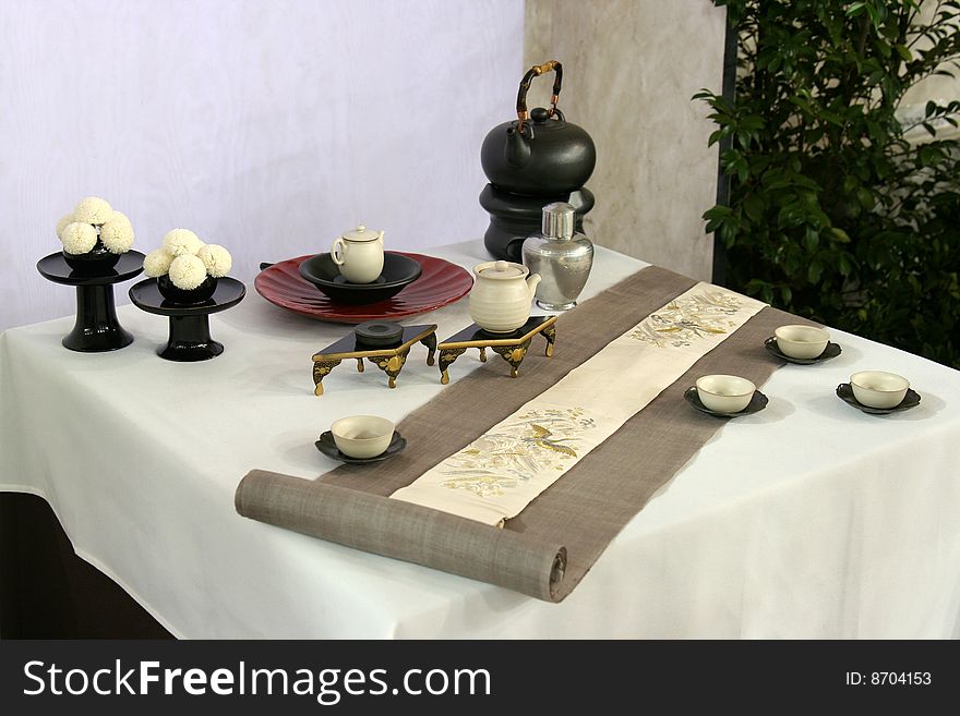 A beautiful table design in Japan.It is consisted of a hanging scroll, some Japanese teacups, a Japanese teapot and two stand for cakes.