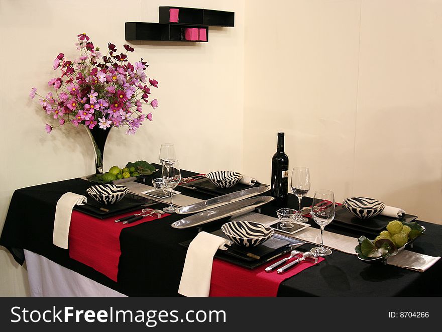 A beautiful table design with dishes,table wares, glasses, a bottle of wine and flower arrangement. A beautiful table design with dishes,table wares, glasses, a bottle of wine and flower arrangement.