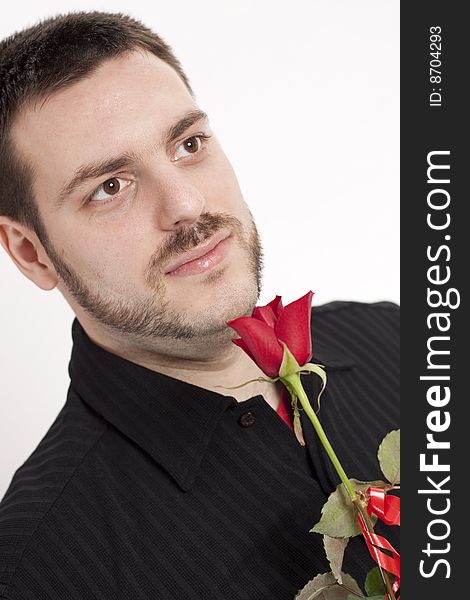 Young, handsome man in a black shirt, with red rose in his hands, waiting, giving a little smile. Young, handsome man in a black shirt, with red rose in his hands, waiting, giving a little smile