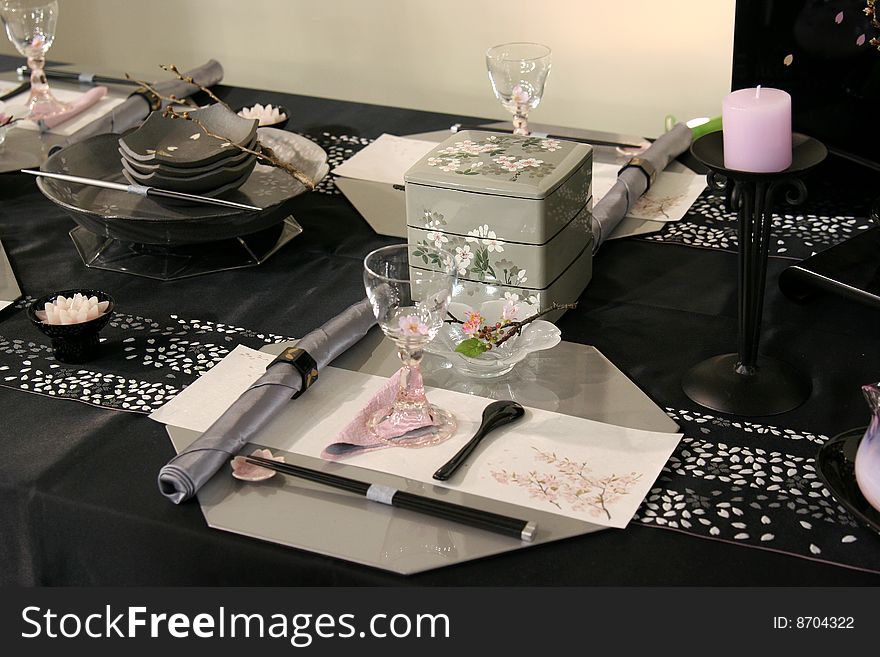 A beautiful table design in Japan.It is consisted of dishes,glasses, towels, a candle with stand and other objects.