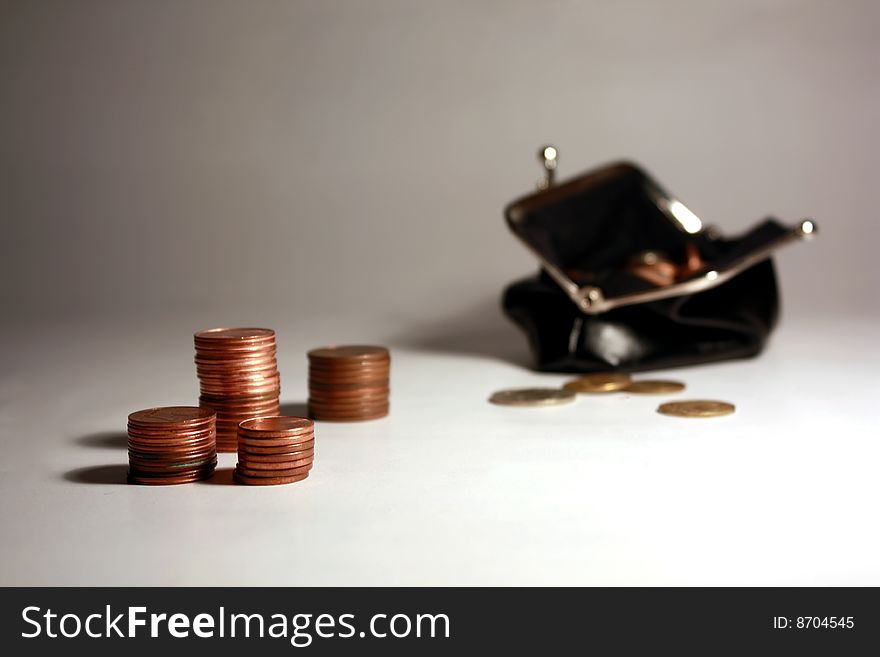 Black purse with coins, and coins lying nearby. Black purse with coins, and coins lying nearby.