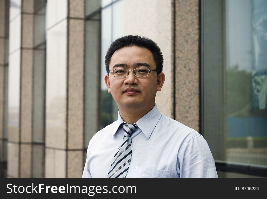 Asian business executive standing in front of office building.