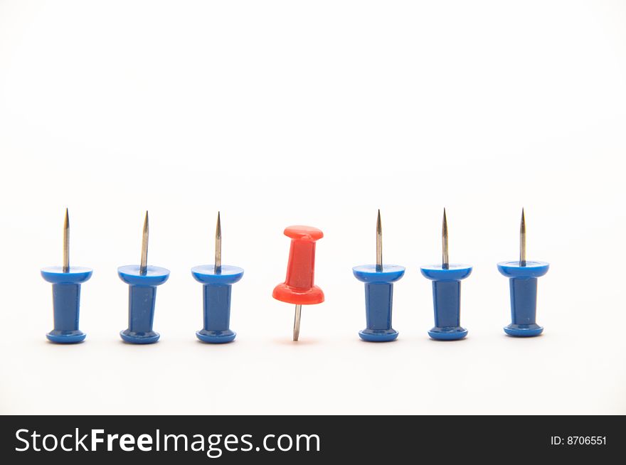 Blue push-pins isolated on white background with a red one pinned down