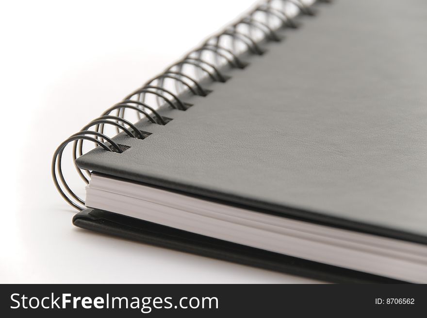 Black spiral notebook on white background, close-up view