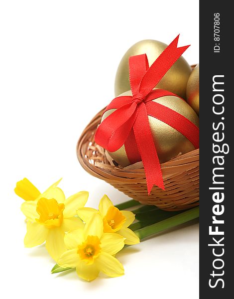 Golden egg wrapped around with red ribbon in basket with daffodils on white background. Golden egg wrapped around with red ribbon in basket with daffodils on white background.