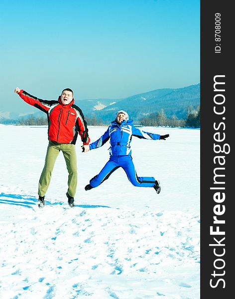 Happy young couple jumping and having fun outdoor in wintertime. Happy young couple jumping and having fun outdoor in wintertime