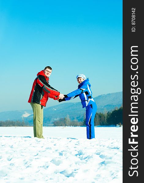 Happy young couple holding hands outdoor in wintertime. Happy young couple holding hands outdoor in wintertime