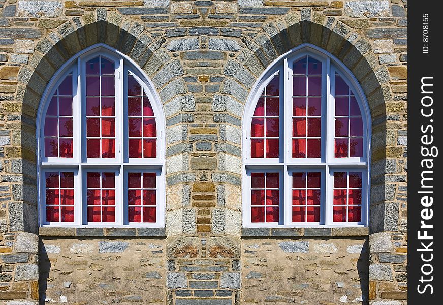 Twin church windows with arches on a stone wall.